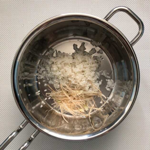 研いだ米とせりの根を鍋に入れた画像
