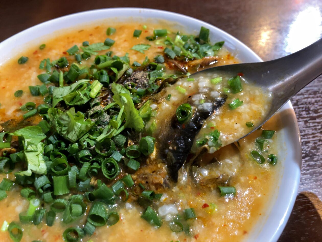 ベトナム中部名物田鰻とハーブ野菜のおかゆをすくっている画像