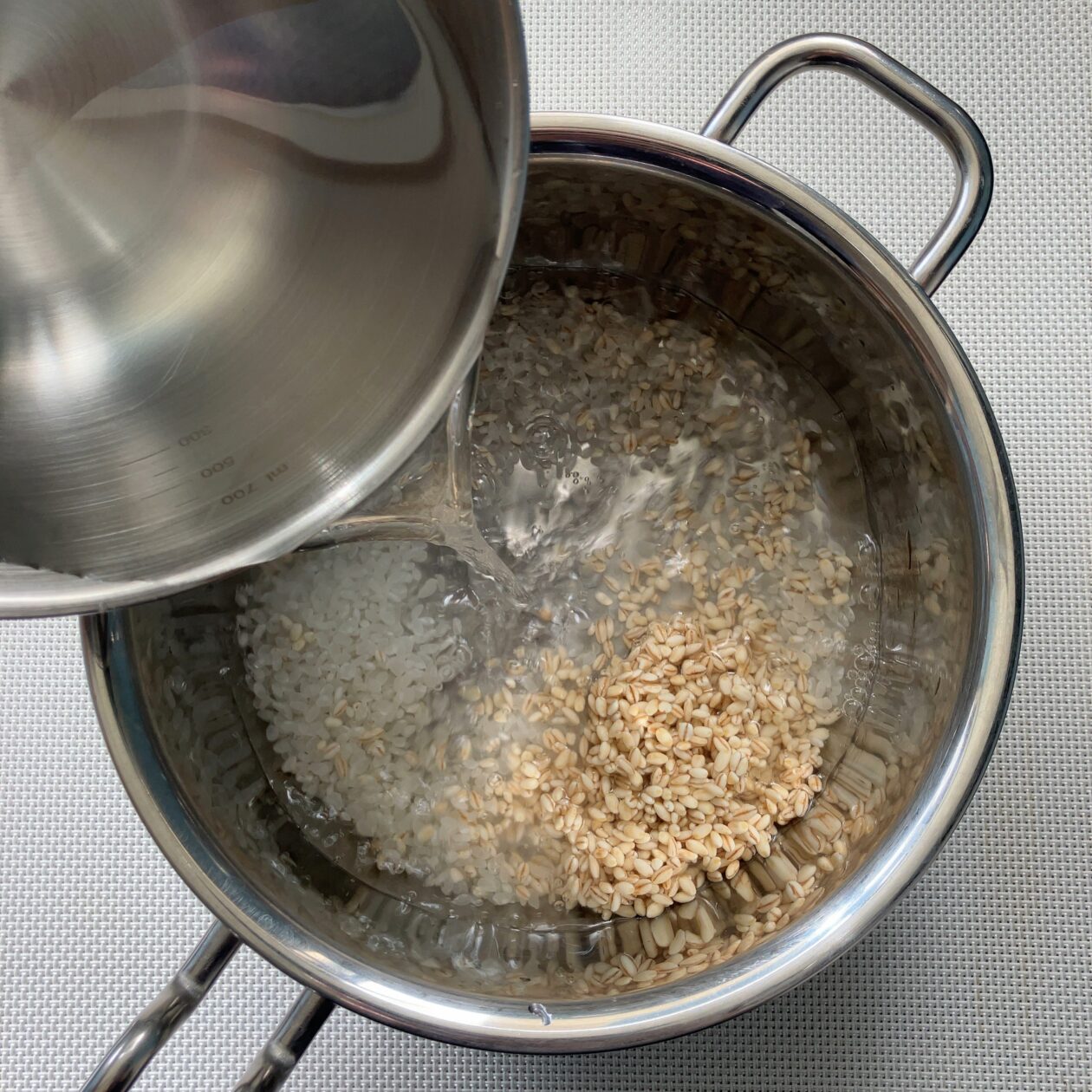 ウクライナのクリスマス粥クチャに使う米と麦を鍋に入れて水を注いでいる画像