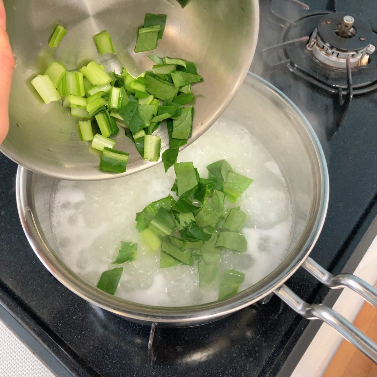 小松菜を鍋に入れている写真