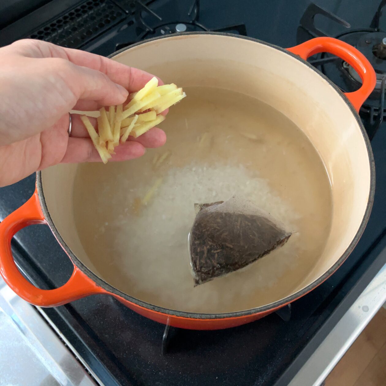 鍋に米、茶葉、生姜を入れている画像