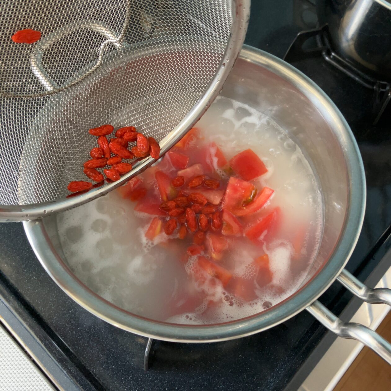 トマトとクコの実を鍋に入れる写真