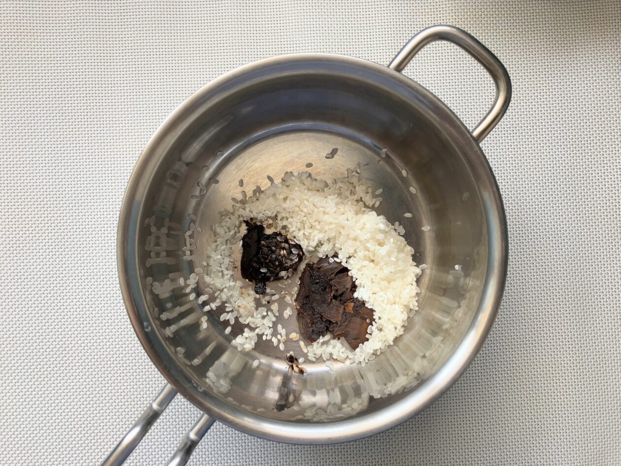 鍋に米と潰した黒にんにくを入れた写真
