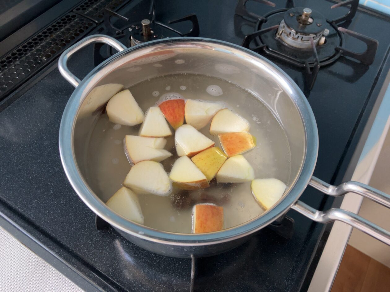 米、りんご、レーズン、水を入れた鍋を火にかけている写真