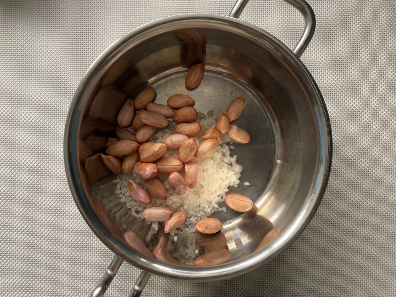 殻を剥いた生ピーナッツと生米を鍋に入れた写真
