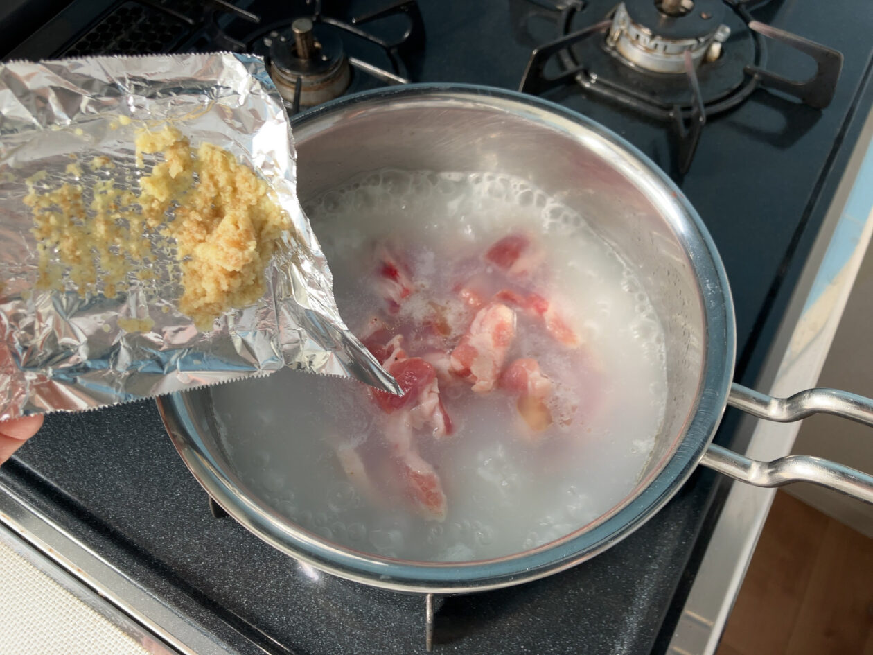 鍋に肉と生姜を入れている写真